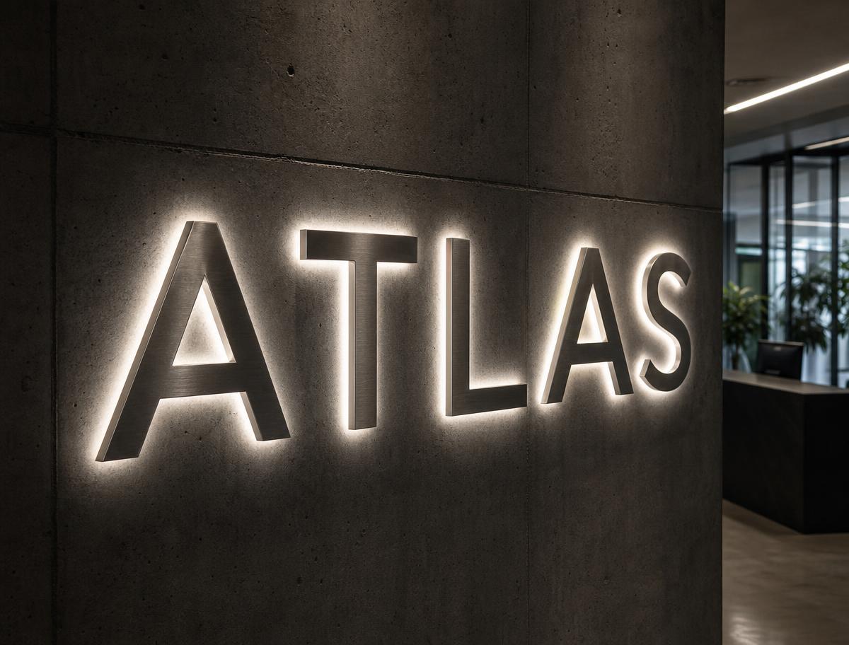 Halo-lit stainless steel letters reading ATLAS on a concrete reception wall