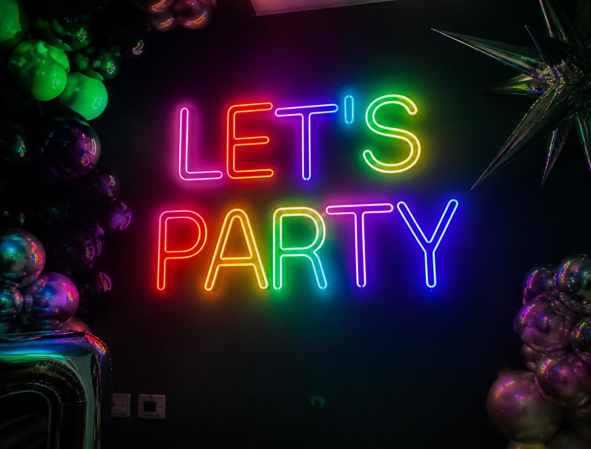 Lets Party LED neon sign glowing at a party venue backdrop