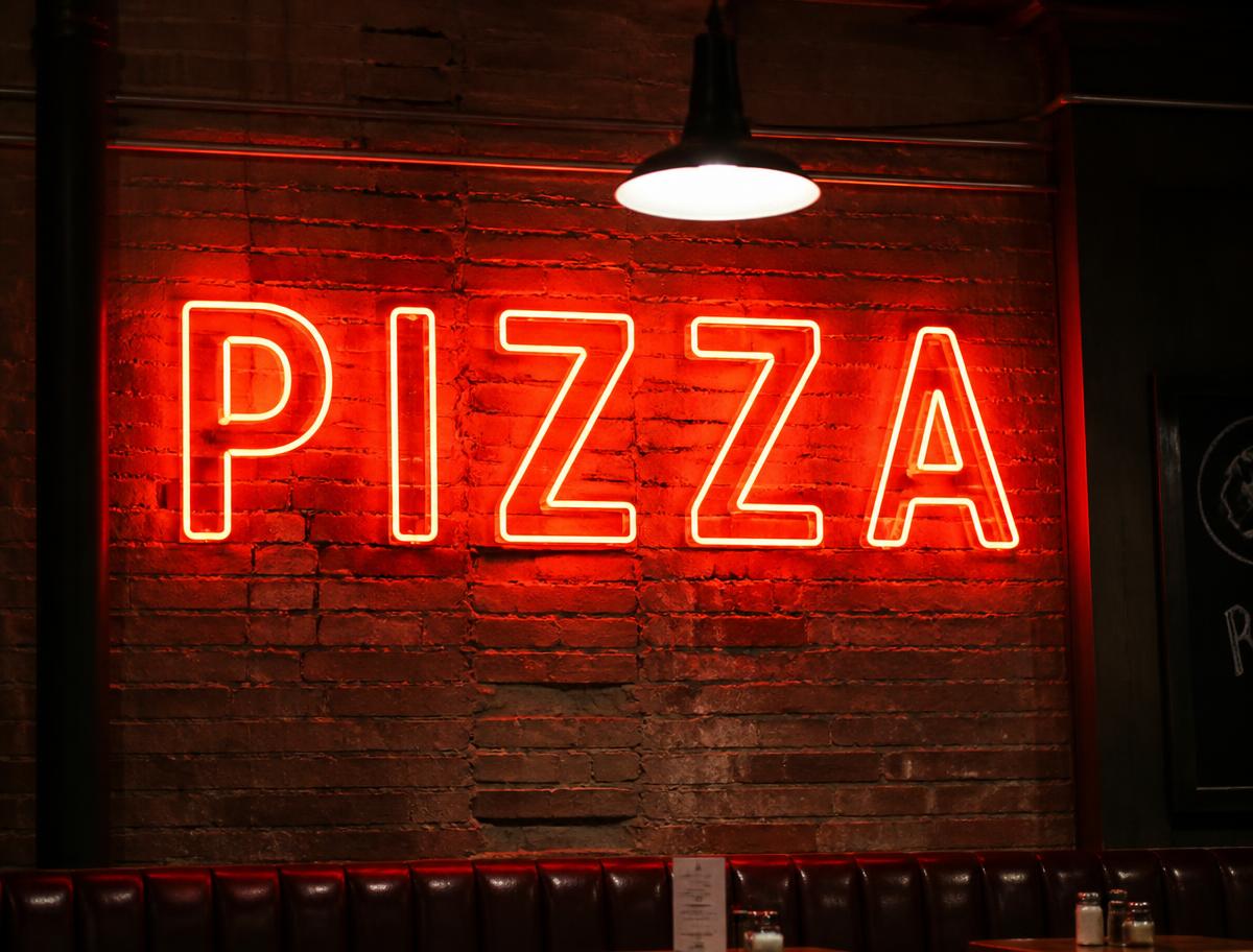 Red Pizza LED neon sign glowing in a pizzeria window at night