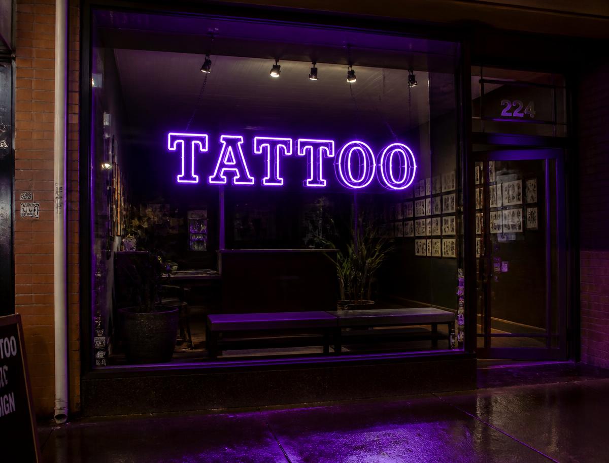 Red Tattoo LED neon sign in the window of a tattoo studio at night